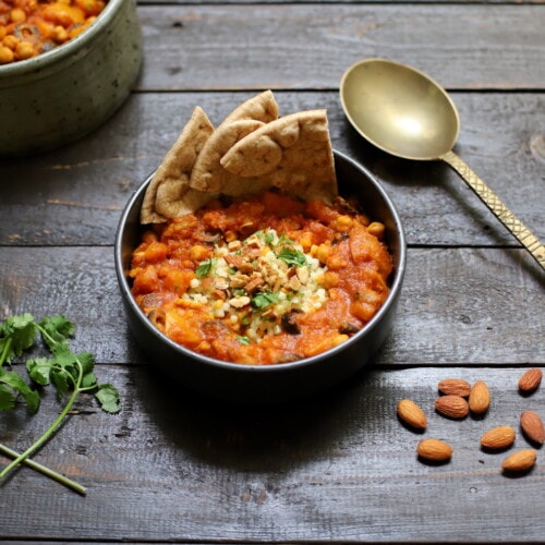 moroccan stew with pita on black board with gold spoon