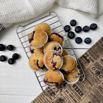 Blueberry muffins on paper with blueberries around.