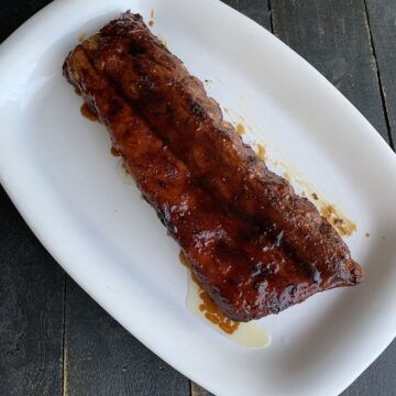 ribs glazed with Guinness beer sauce on a white plate on a black board