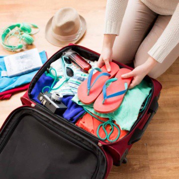 Packing a suitcase with hat and headphones on side.
