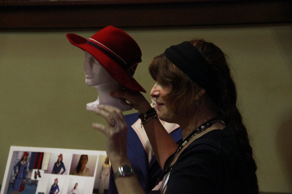 Gigi Melton is the designer behind the fabulous fashion on Agent Carter. Here she holds an idea board showing how she comes up with ideas for what Hayley Atwell and the rest of the cast will wear. In this photo Gigi Melton holds red hat.