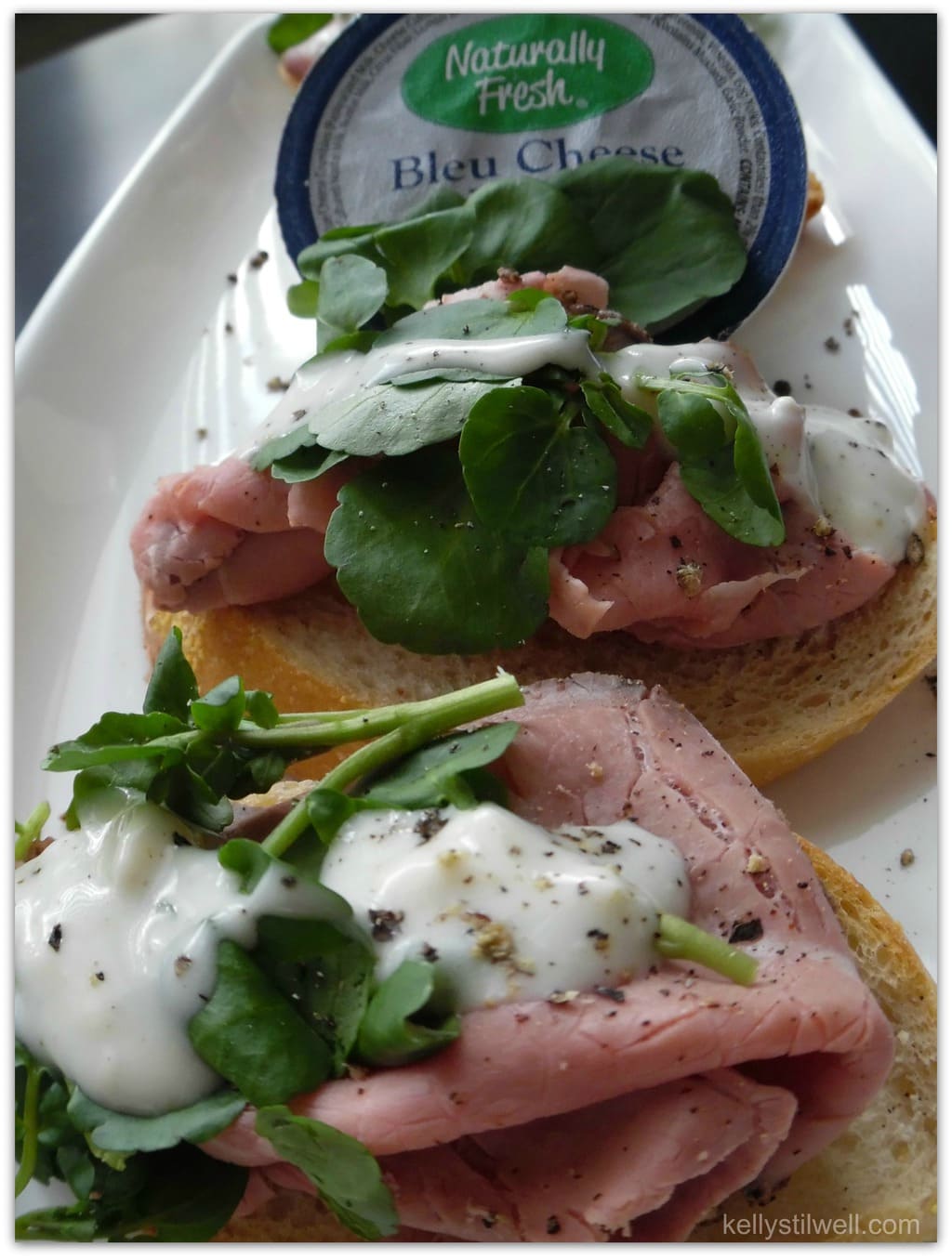 Roast beef on a slice of baguette with watercress and bleu cheese dressing.
