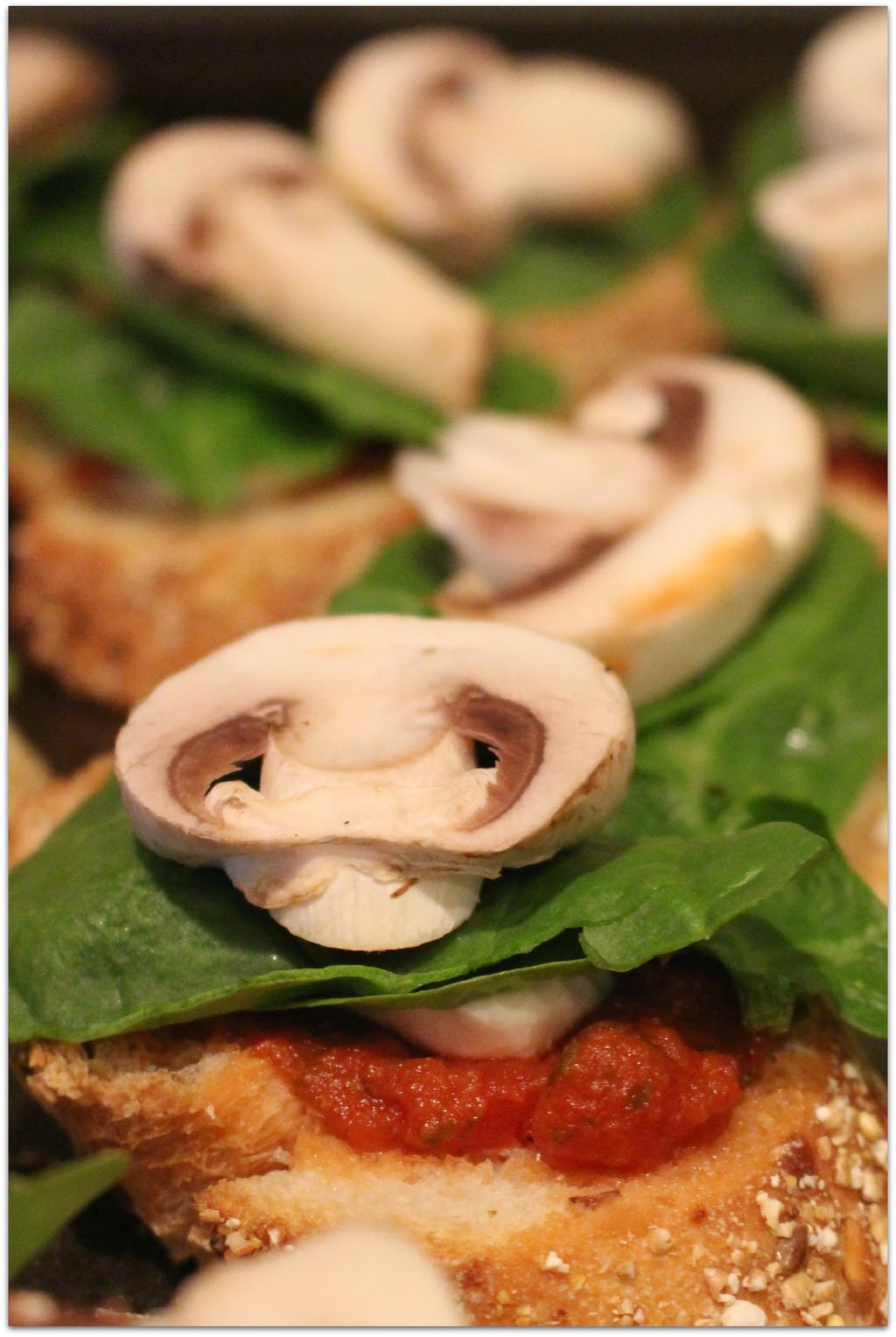 Mushroom and spinach on bread with sauce and mozzarella.