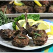 Lamb chops with lemon on a white plate.