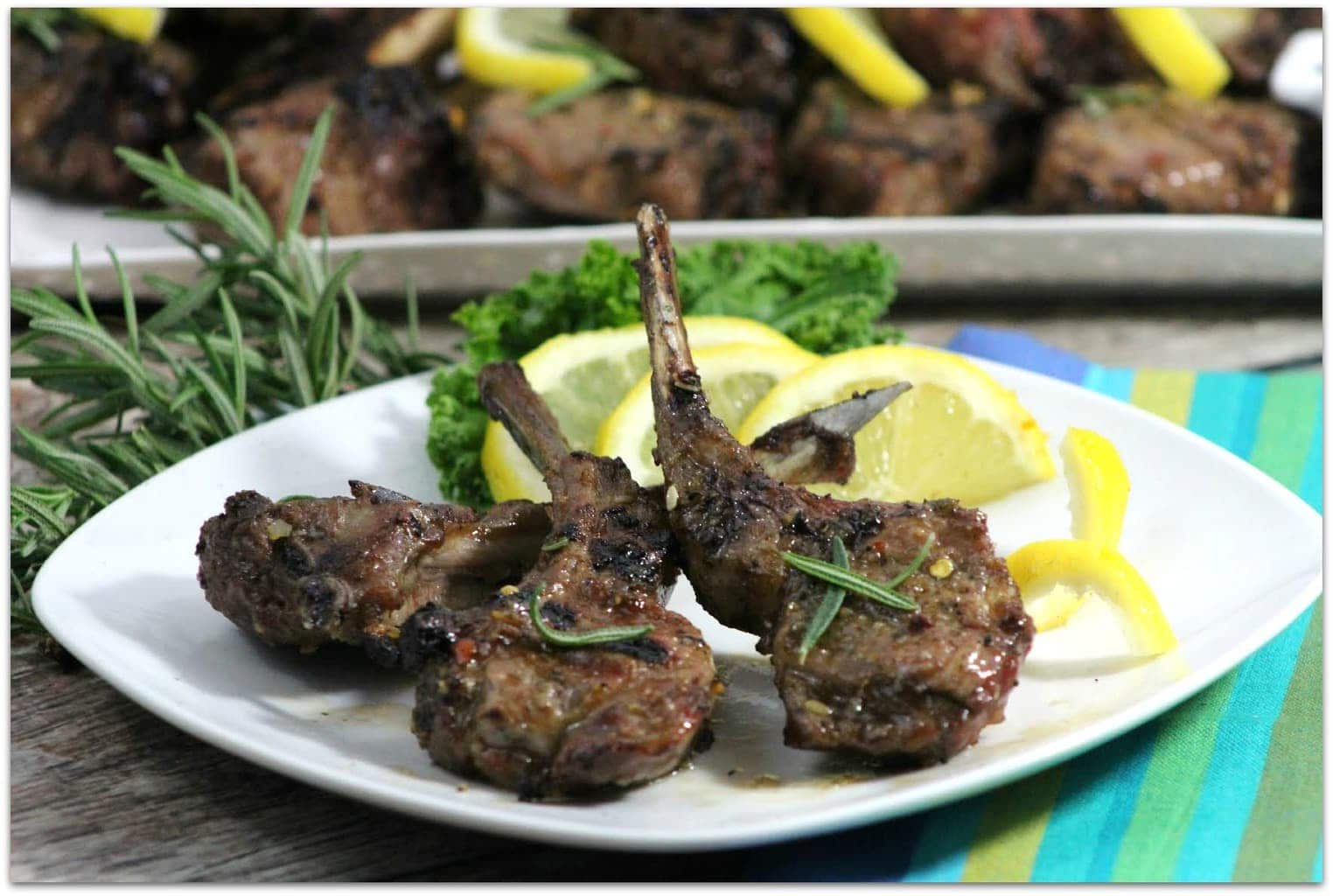 Lamb chops grilled on a white plate with lemons.