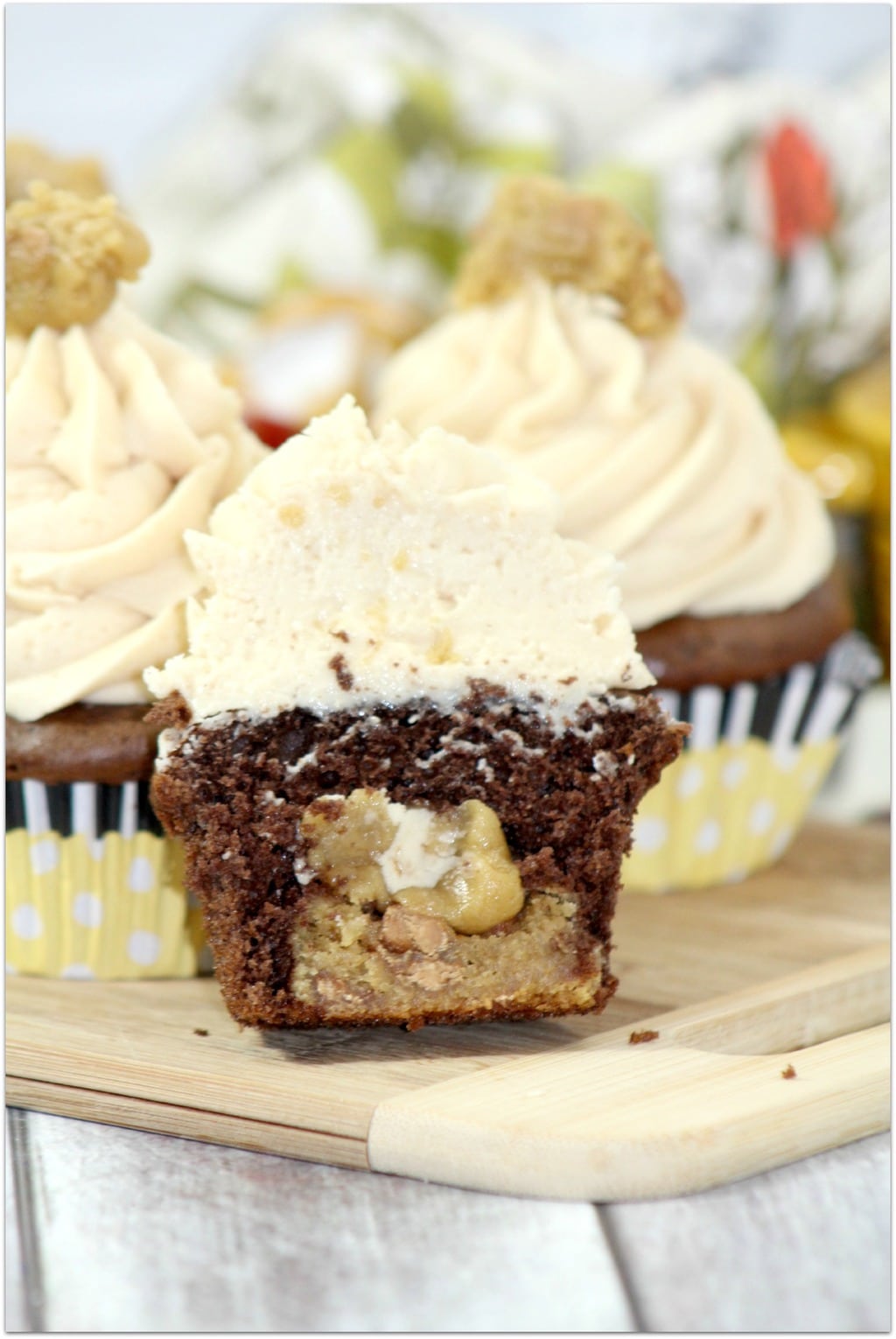 Chocolate peanut butter cupcakes with peanut butter frosting and pinch of peanut butter on top.