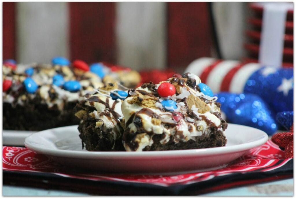 Red, white and blue brownies on a table with patriotic decorations.