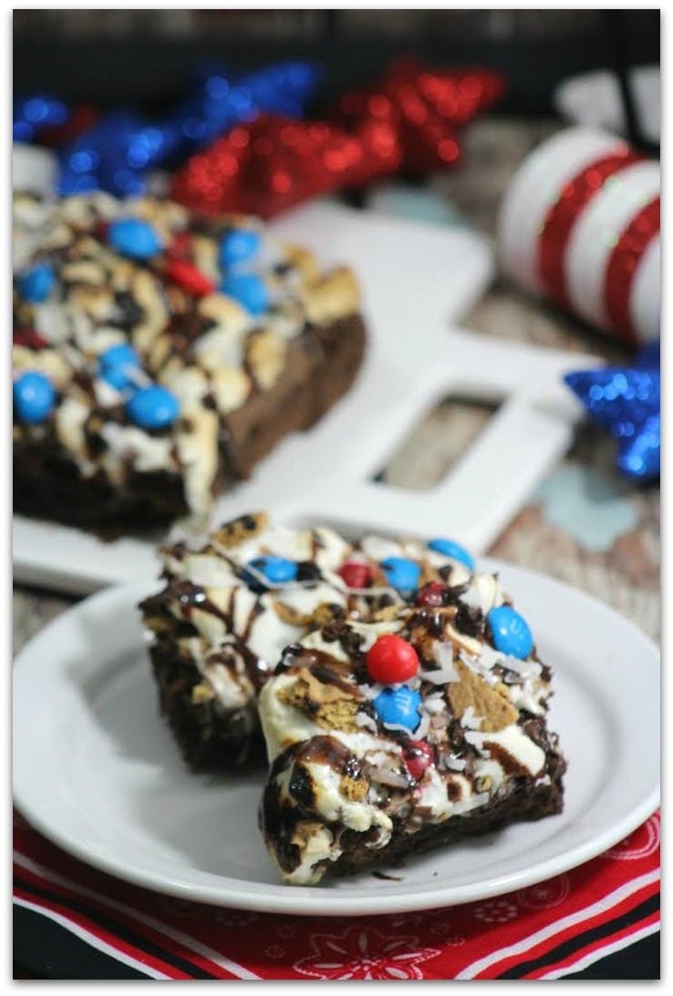 Red, white and blue brownies on a table with patriotic decorations.