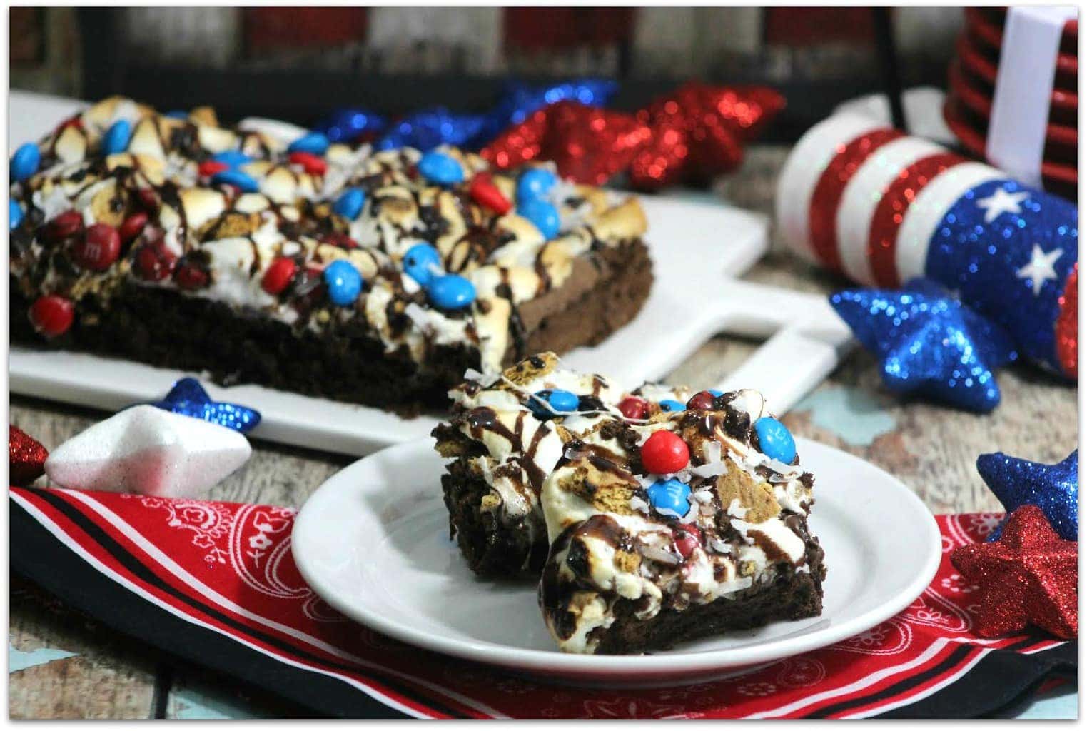 Red, white and blue brownies on a table with patriotic decorations.