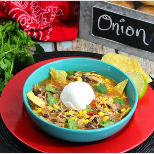 Tortilla soup in a blue bowl on a red placemat.