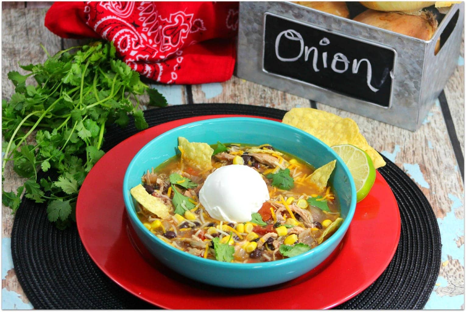 Tortilla soup in a blue bowl on a red placemat.