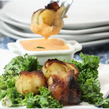 Bacon wrapped scallops on plate and on a fork over dipping sauce.