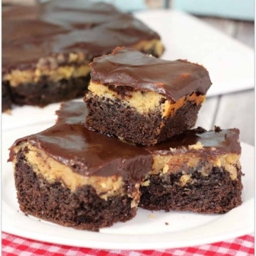 Chocolate peanut butter bars on a white plate on a red checked tablecloth.