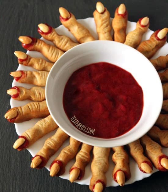 Bread sticks made into fingers with sauce in white bowl.
