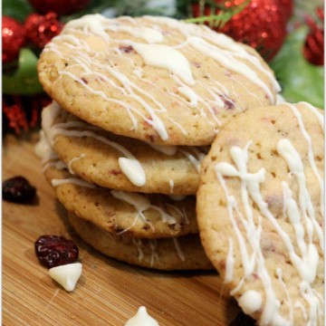 Cranberry Cookies with white chocolate drizzle on cutting board.