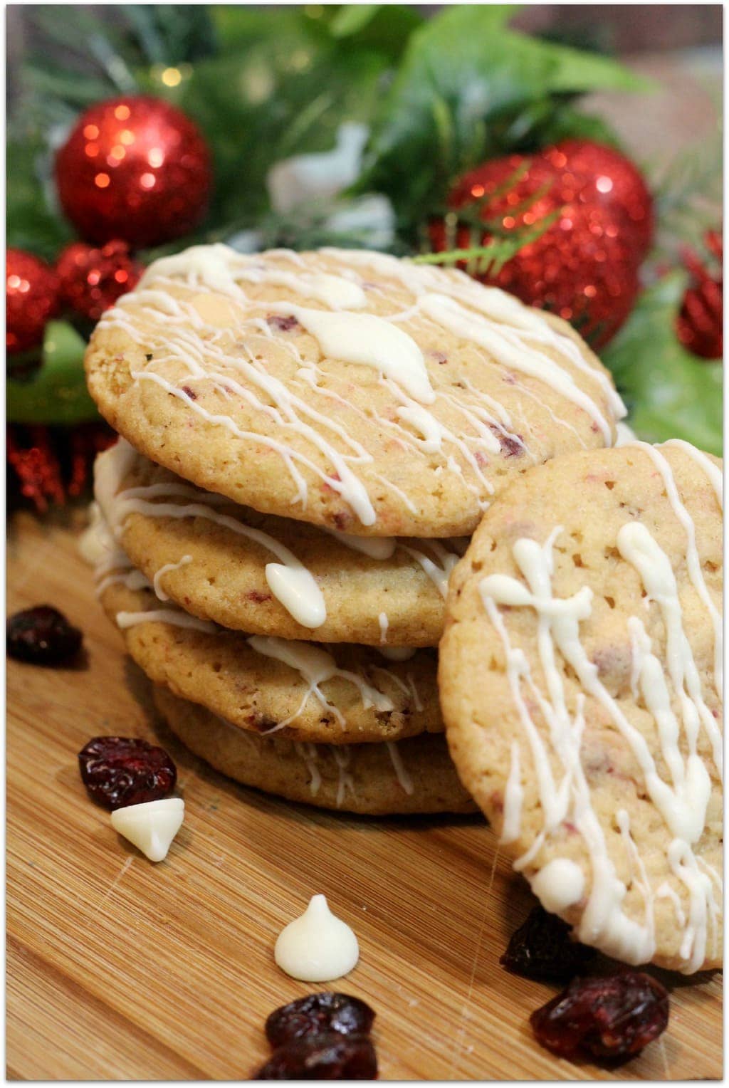 Cranberry Cookies with White Chocolate Drizzle on cutting board with festive decor.