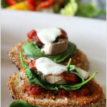 Toasted fresh mozzarella with spinach and tomato sauce on bread.