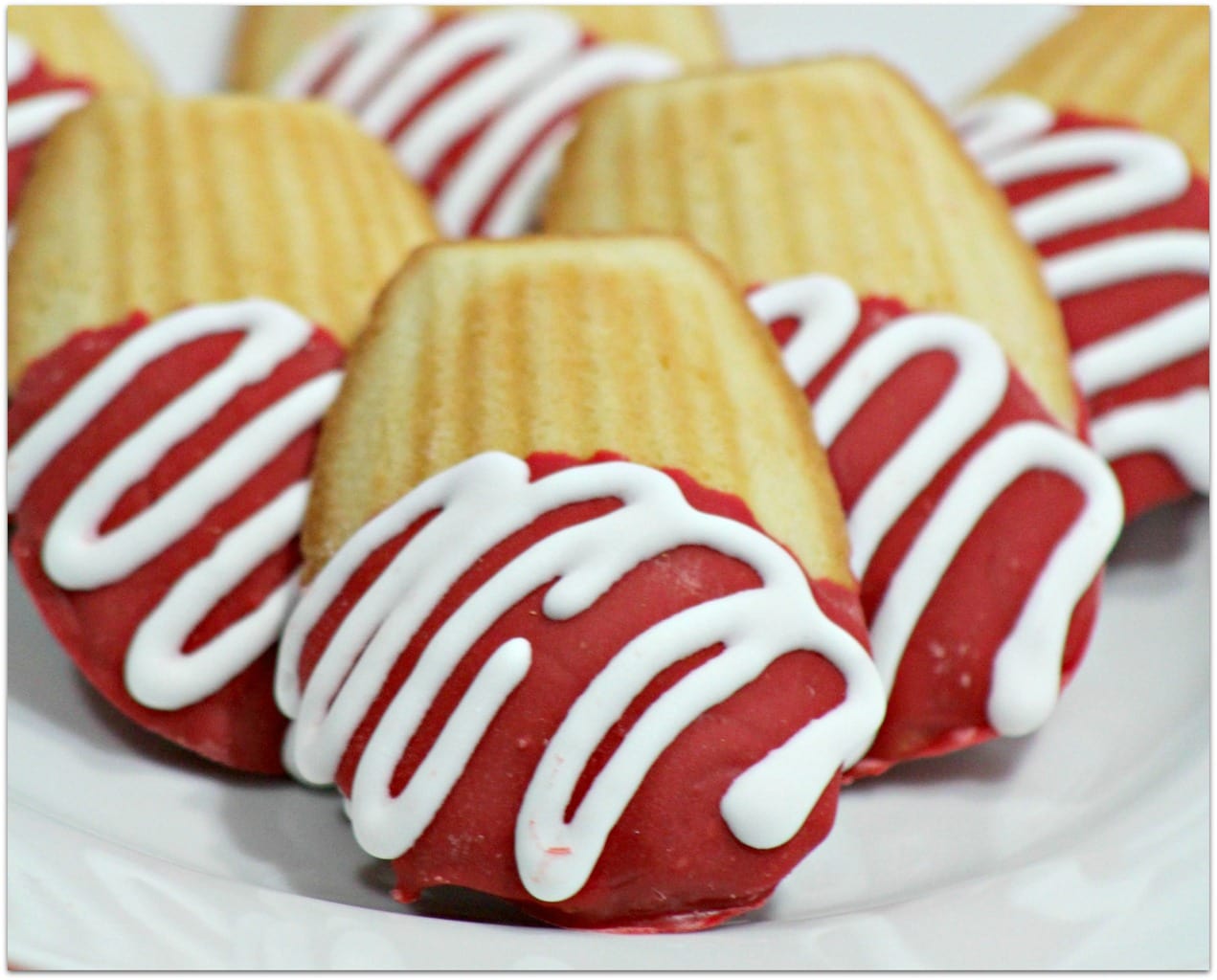 Red and white chocolate dipped  cookies on a white plate.
