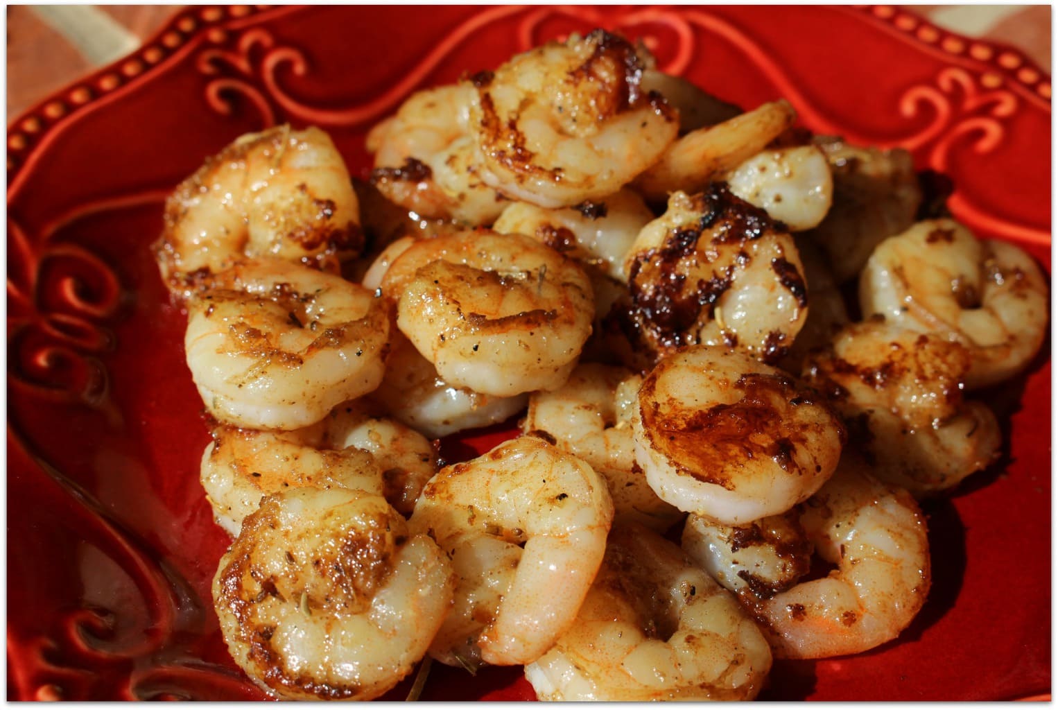 Grilled shrimp on red plate.