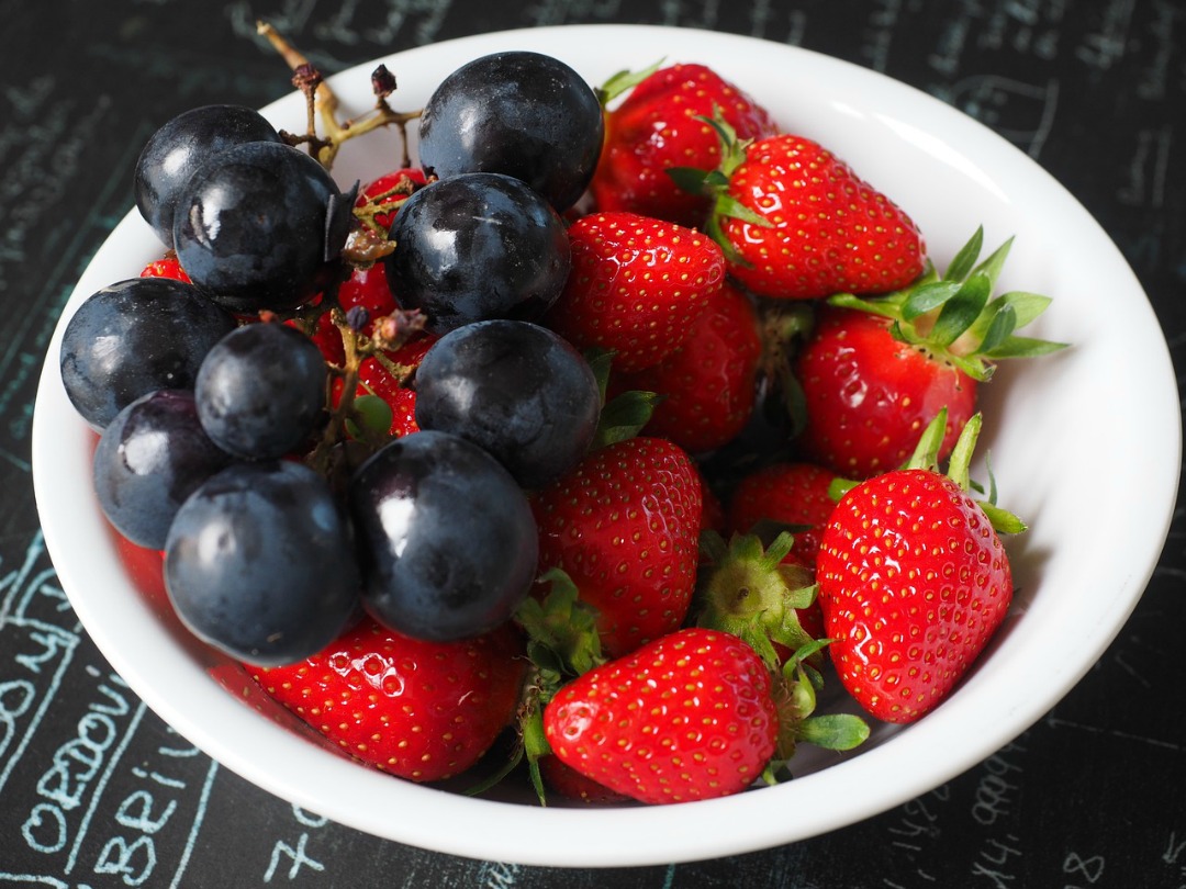 Strawberries and blueberries in a white bowl.