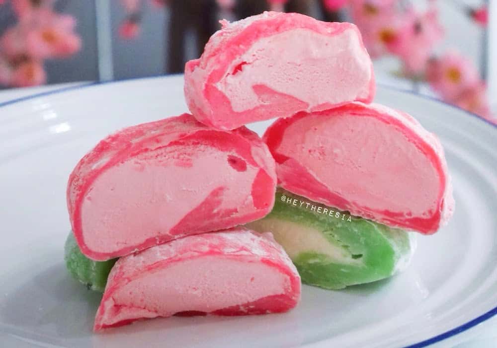 Pink and green ice cream balls on white plate.