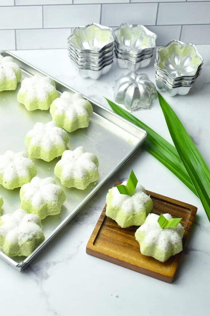 Small green flower shaped cakes on a baking sheet.