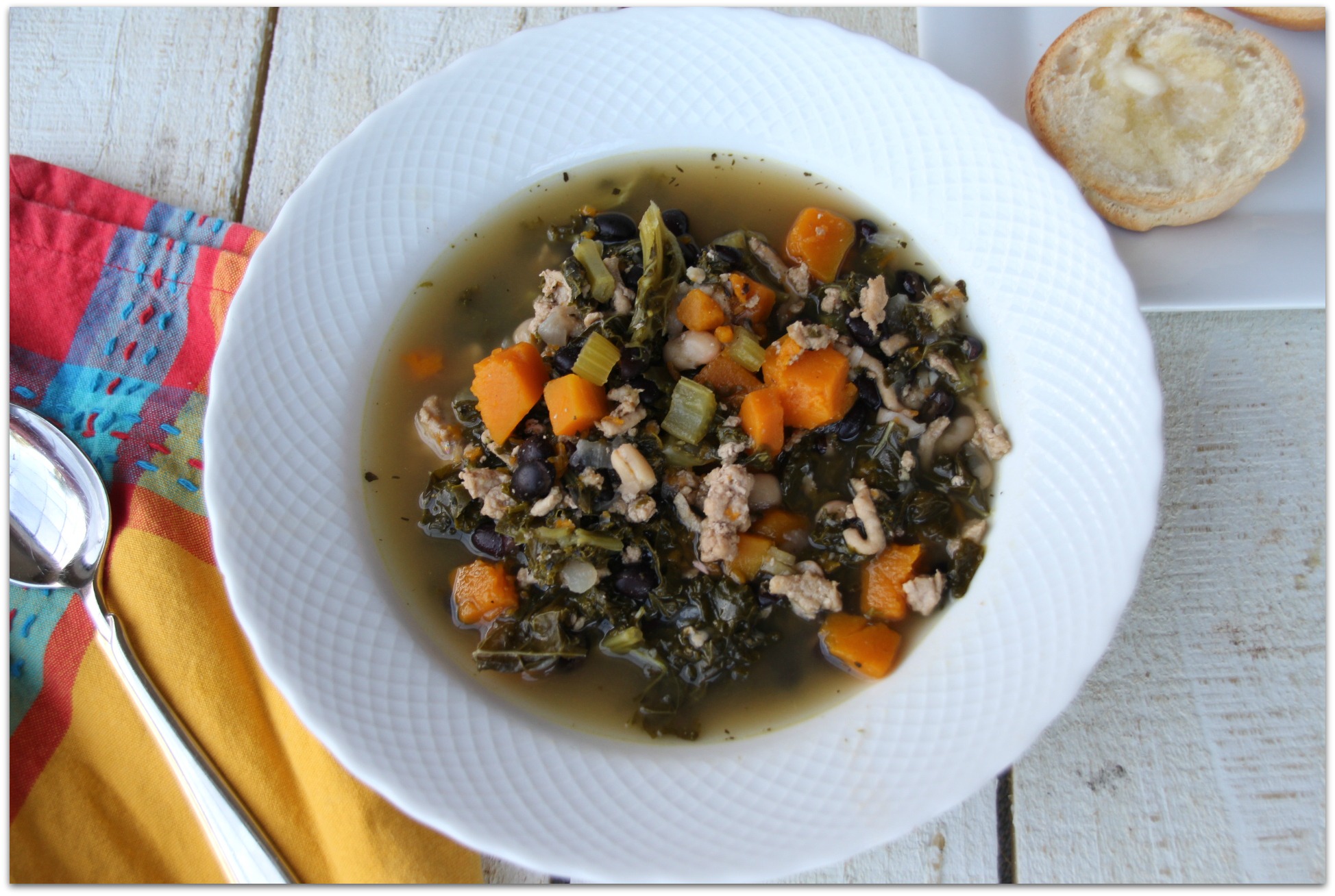 soup with turkey and butternut squash on a white board with a orange and red napkin