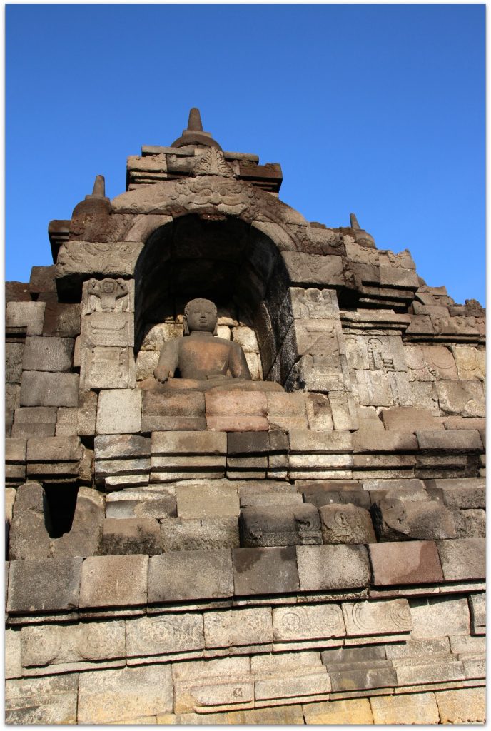 Buddha statues in stone with blue sky in background.