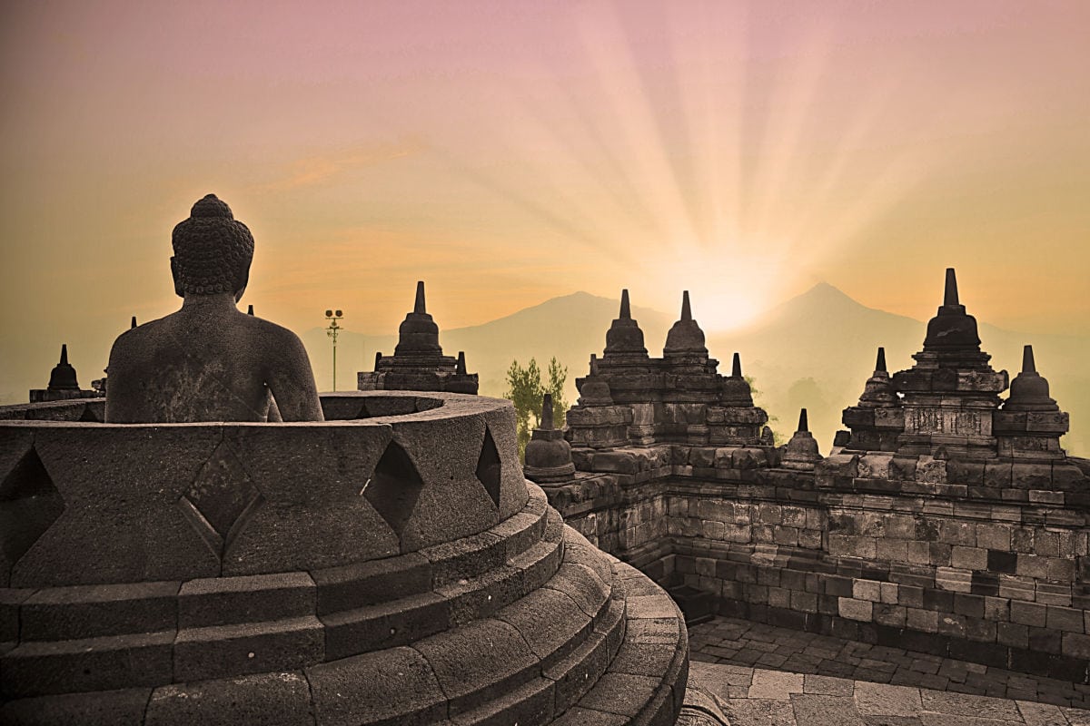 Buddhist temple with sunlight behind a mountain.