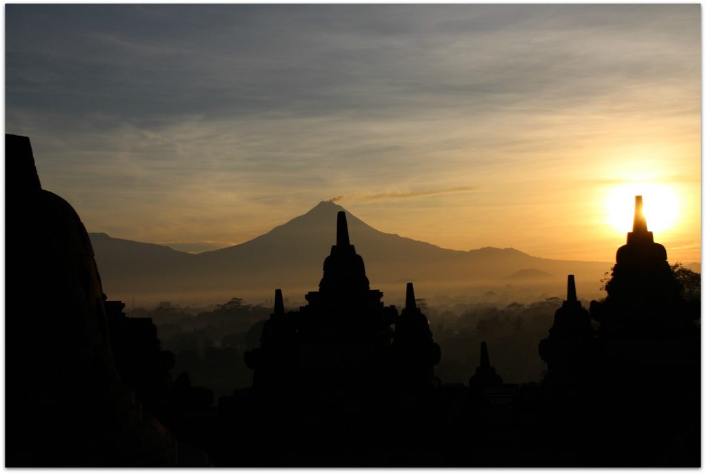 Sunrise beyond a volcano and temple.