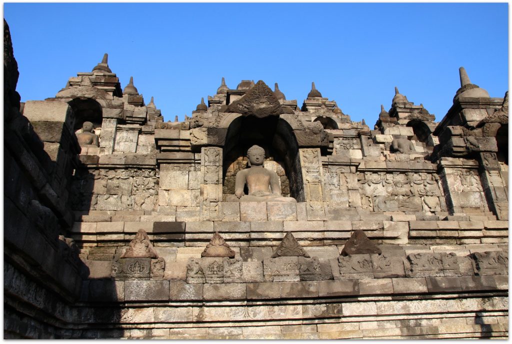 Buddha statues in stone with blue sky in background.