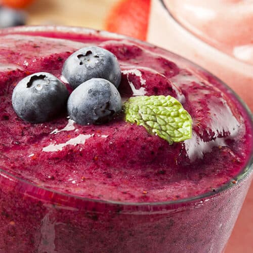Purple smoothie with blueberries and mint on top.