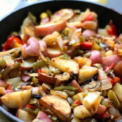 Potatoes with onions and peppers in a skillet.