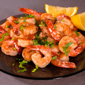 Cooked shrimp on plate with lemons.