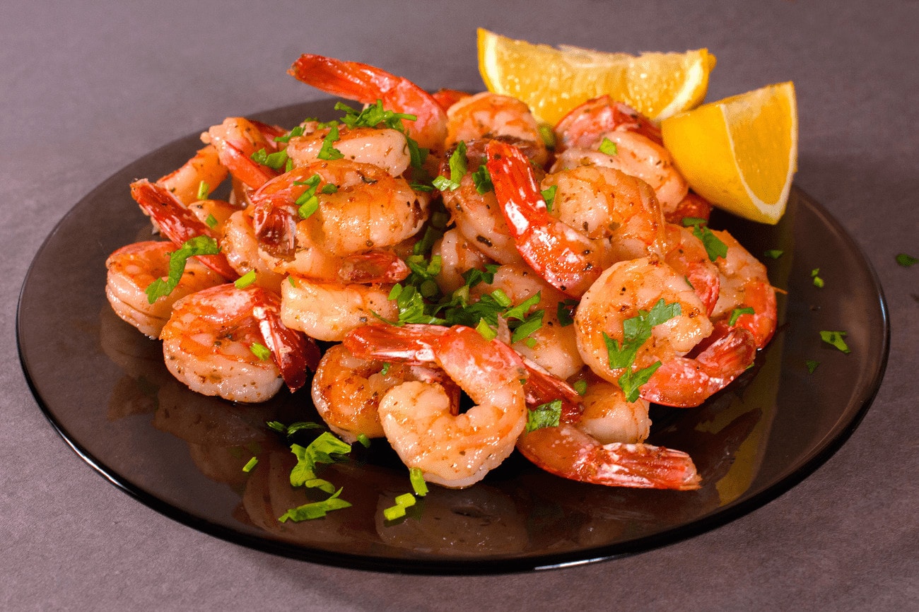 Cooked shrimp on plate with lemons.