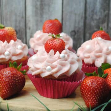 Strawberry cupcakes on a wood board.