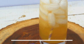 Lavender lemonade in a glass with a straw and slice of orange.