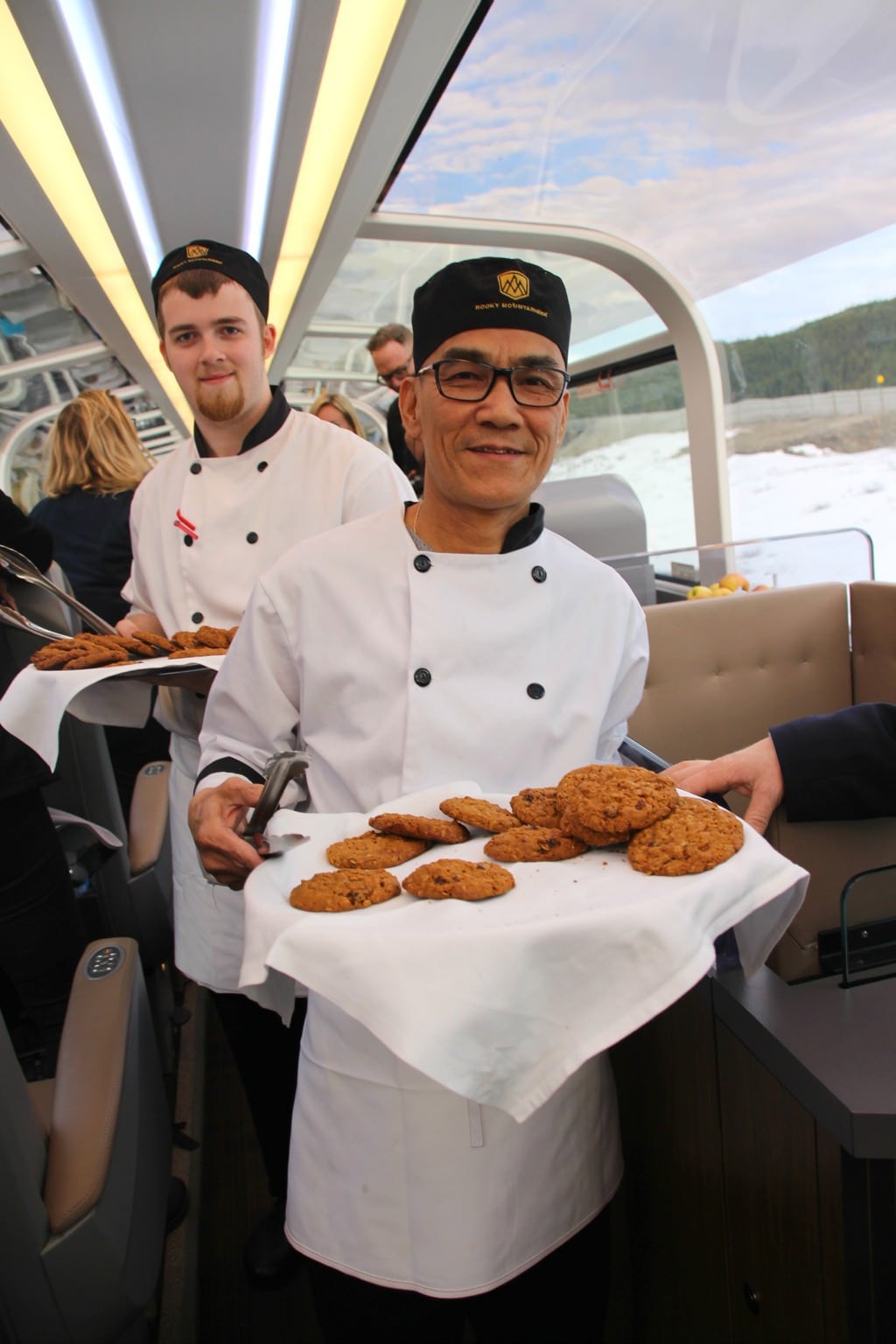 Rocky Mountaineer staff serving cookies on train