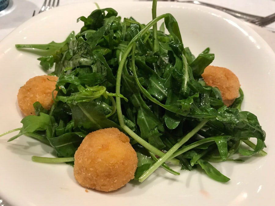 Salad with fried cheese on a white plate.