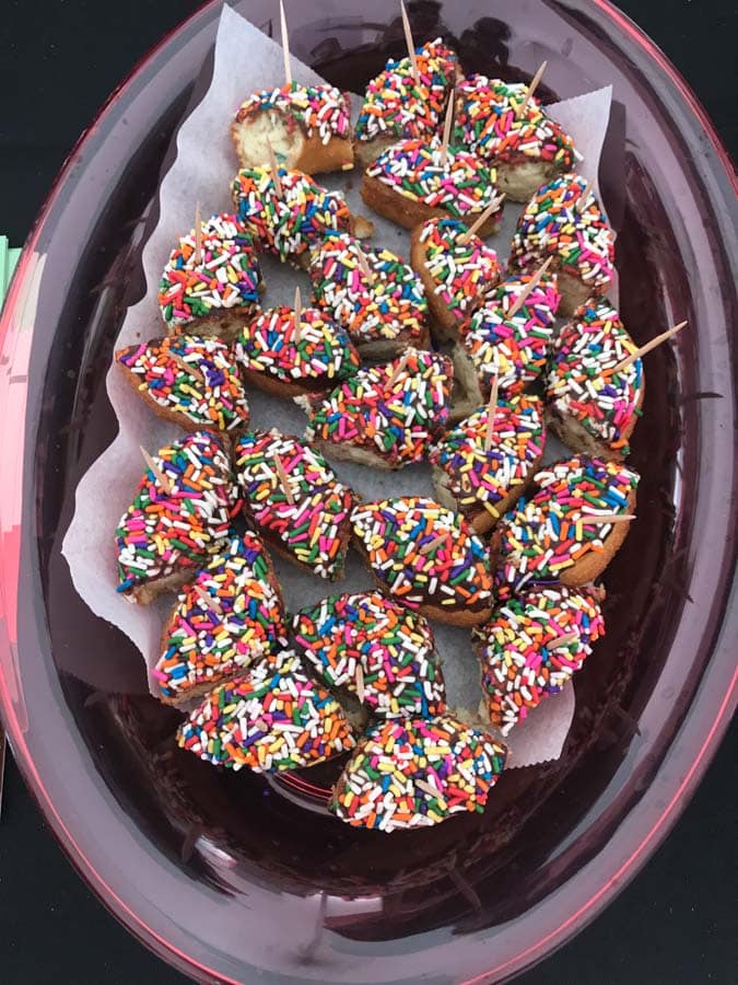 Plate of donuts with sprinkles cut up.