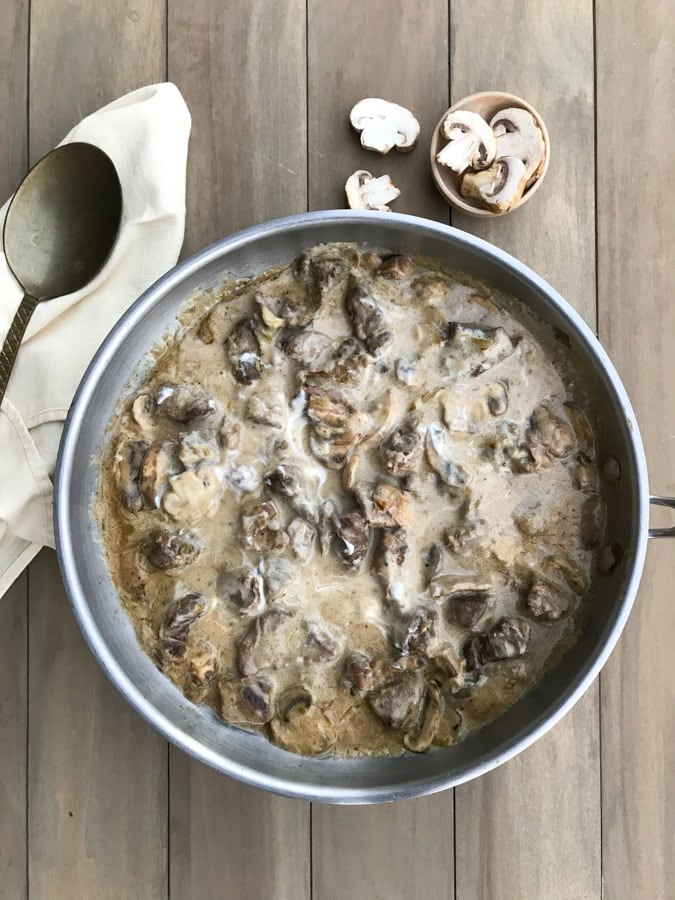 beef stroganoff in stainless pan with spoon on a wood board 