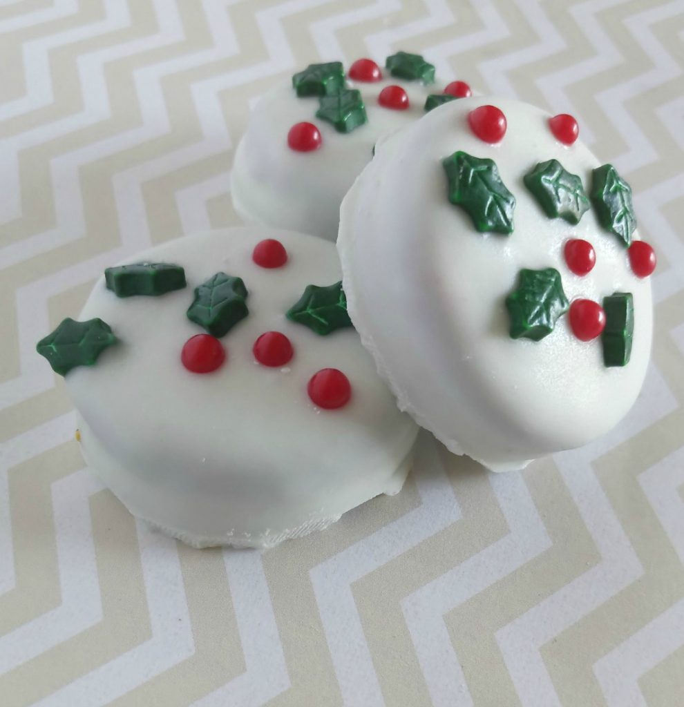Oreos covered in white chocolate with holly decoration.