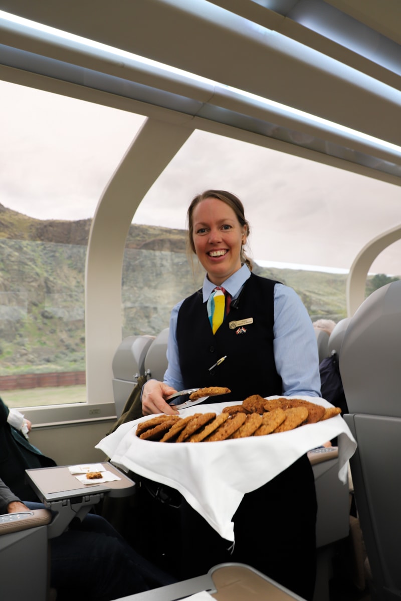 Rocky Mountaineer team member serving cookies.