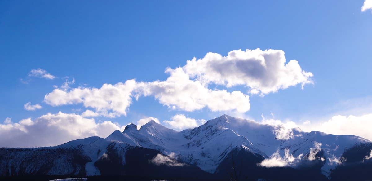 Snow covered mountains and blue sky with white clouds.