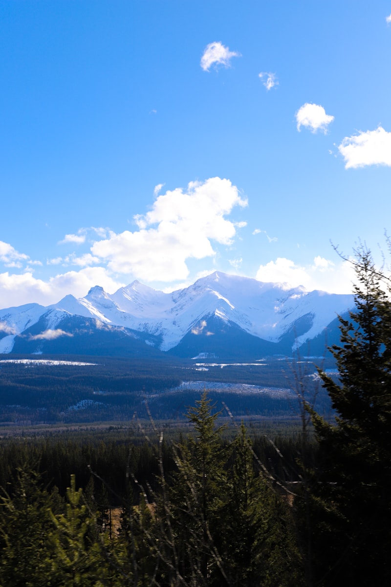 Snow covered mountains against blue sky with white clouds.