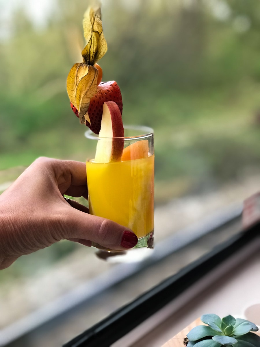 Glass of juice in front of window on Rocky Mountaineer Train. 