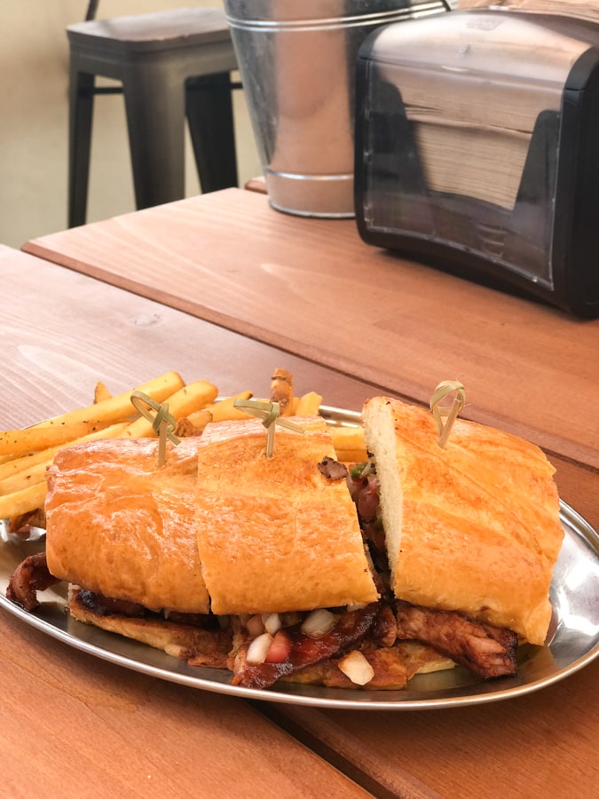 Sandwich with french fries on picnic table.