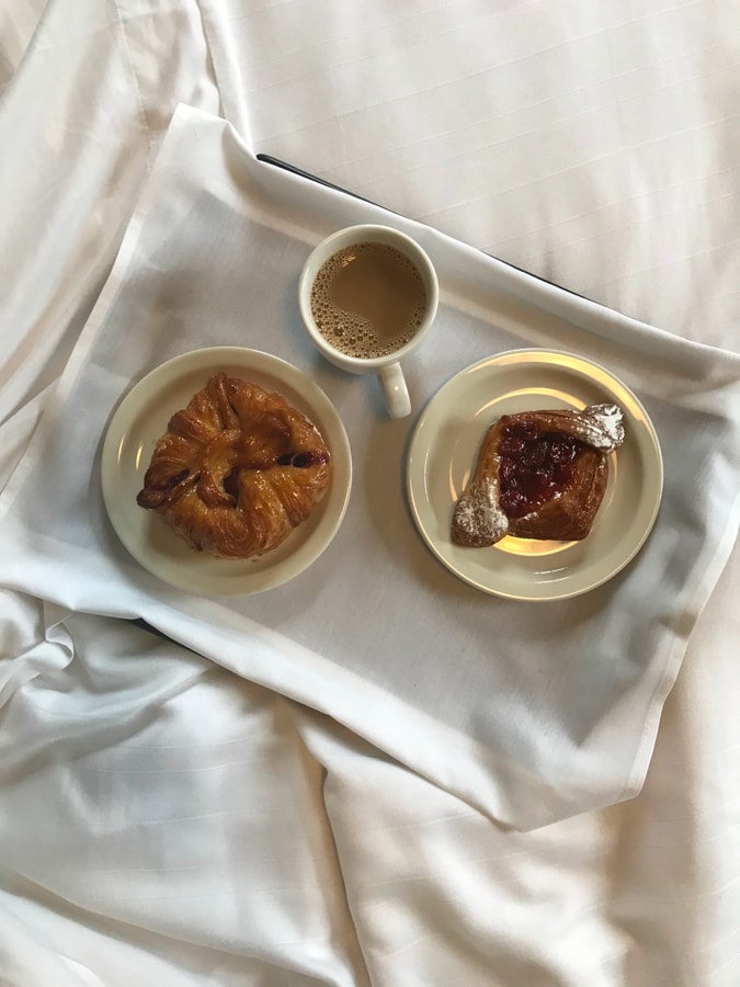 Pastries on a bed with cup of coffee.