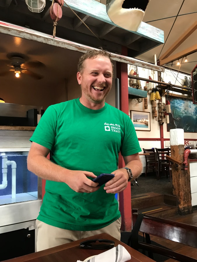 Tour guide in green shirt laughing at restaurant.