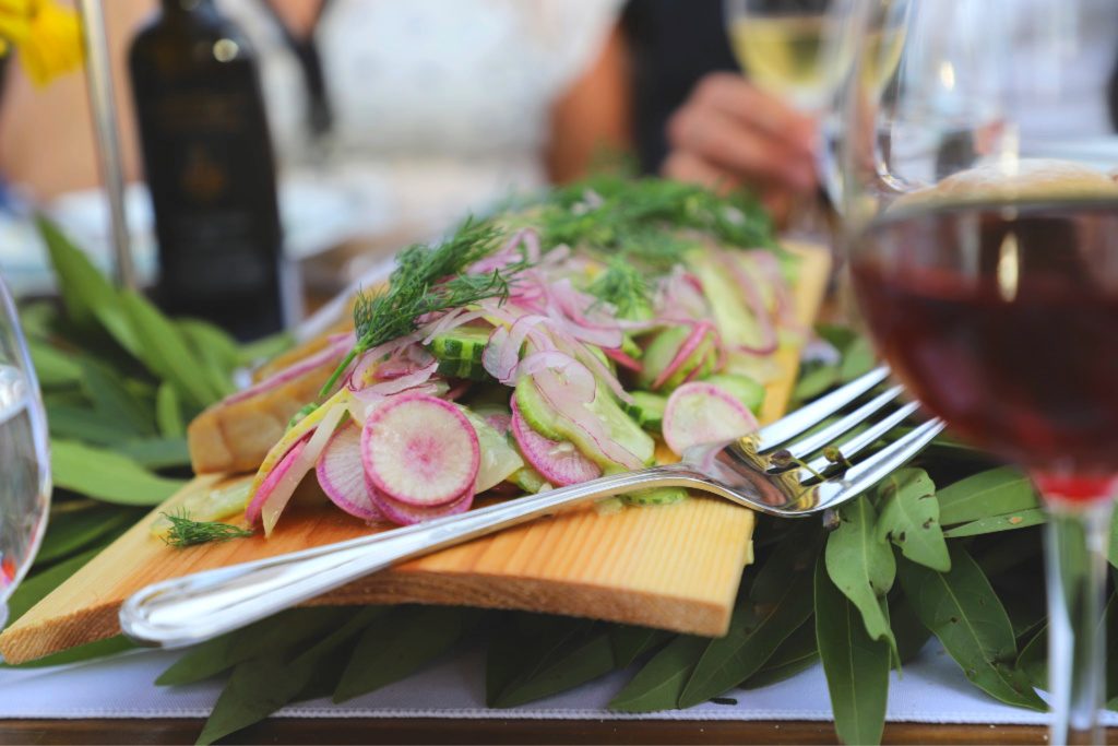 sturgeon, dill, greens, and radishes on a wood board